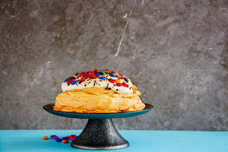 Meringue cake Pavlova with colorful Sprinkles, whipped cream and chocolate on cake standの写真素材