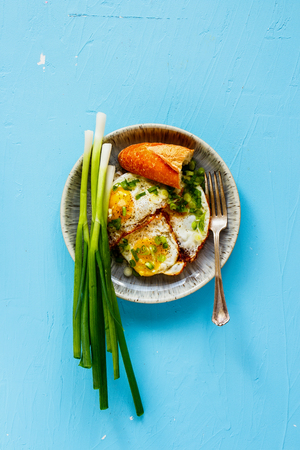 Fried eggs on blue background captured from above flat layの写真素材