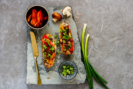 Flat-lay of hot mushroom toasts with grilled bell pepper on stone board captured from aboveの写真素材