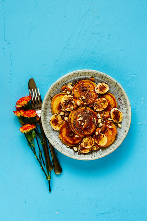 Pancakes with banana, chocolate and almond on blue background flat lay top viewの写真素材