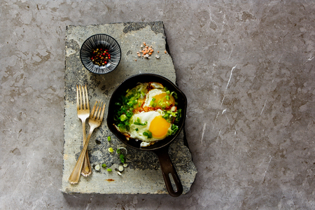 Breakfast, flat-lay of fried eggs in frying pan over stone board from aboveの写真素材