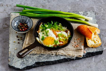 Fried eggs in frying pan over stone board close upの写真素材