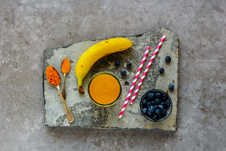 Flat-lay of Mango banana turmeric smoothie on stone board top viewの写真素材