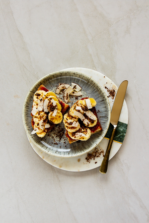 Flat-lay of Banana toast with coconut chips and chocolate, healthy snack top viewの写真素材