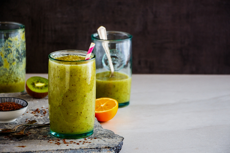 Fresh green smoothie in jars and ingredients on stone boardの写真素材