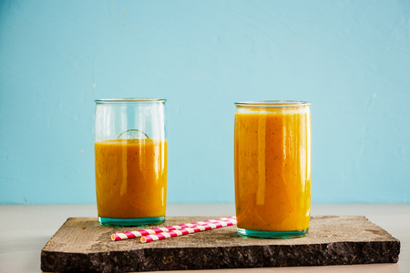 Homemade mango banana turmeric smoothie jars on blue backgroundの写真素材