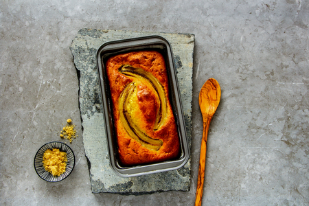 Flat-lay of banana bread cake dessert in baking tin over grey concrete table background, top viewの写真素材