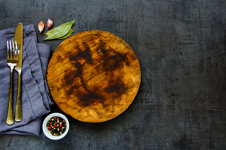Round wooden Cutting board and Spices for cooking on dark concrete backdrop Surface copy space for design text flat layの写真素材