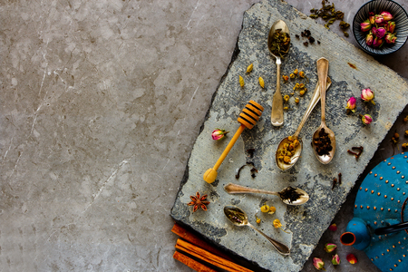 Flat-lay of dry tea and spices on stone board. Tea types backgound from aboveの写真素材