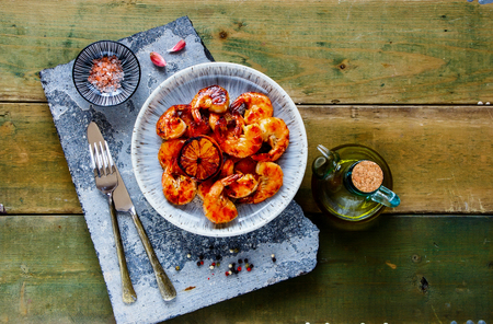 Flat-lay of Grilled pink Prawn Shrimp and lemons on stone board captured from aboveの写真素材
