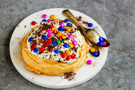 Tasty Pavlova cake with colorful Sprinkles, whipped cream and chocolate close upの写真素材