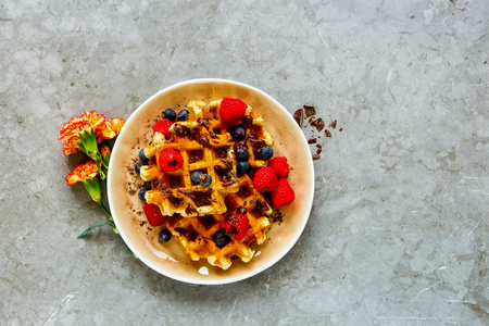 Flat-lay of Belgian waffles with berries and chocolate in plate captured from aboveの写真素材