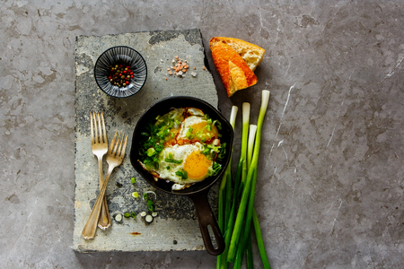 Breakfast with fried eggs in frying pan over stone board from above flat layの写真素材