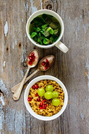Homemade granola with fruits and mint tea on rustic background, flat layの写真素材