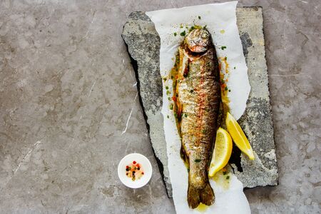 Baked Trout Fish with Herbs and Lemon, top view, flat layの写真素材