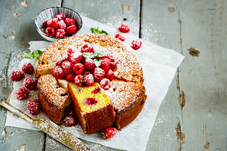Sliced raspberry yoghurt cake on wooden board close up