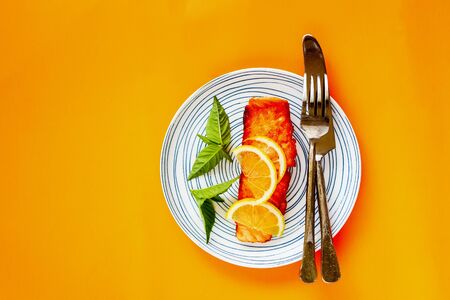 Grilled salmon fish with lemon on orange background, flat lay compositionの写真素材