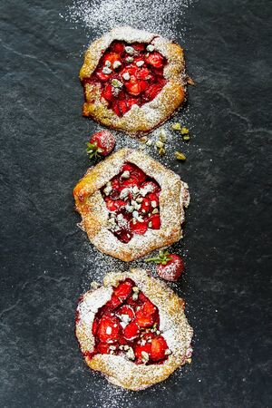 Three homemade strawberry pies with pistachios top viewの写真素材