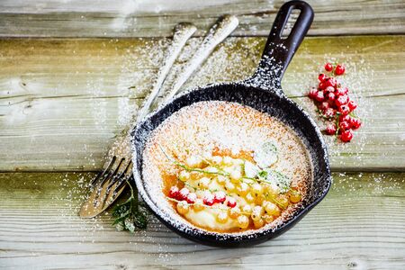Danish pancake with red and white currant berries in frying pan close upの写真素材