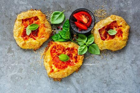 Mozzarella cheese and tomato puff pastry galette flat lay. Tomatoes, cheese, basil pie top viewの写真素材