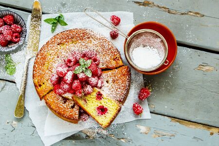 Sliced homemade raspberry yoghurt cake on wooden board, flat layの写真素材