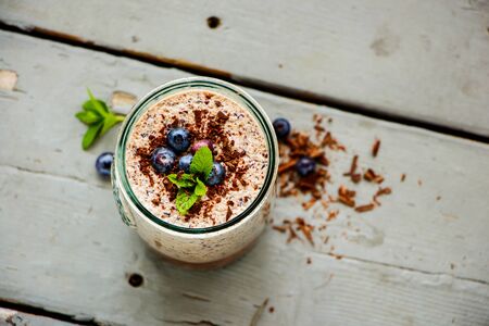 Homemade blueberry milkshake in jar with chocolate on wooden board flat layの写真素材