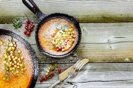 Danish pancake with red and white currant berries in frying pan, flat lay compositionの写真素材