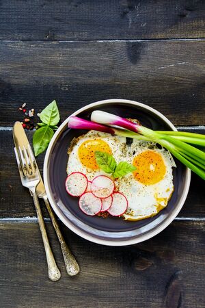Fried breakfast eggs, served with fresh vegetables flat-layの写真素材