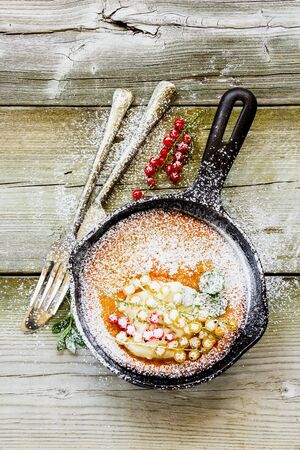Flat-lay of Danish pancake with red and white currant berries in frying panの写真素材