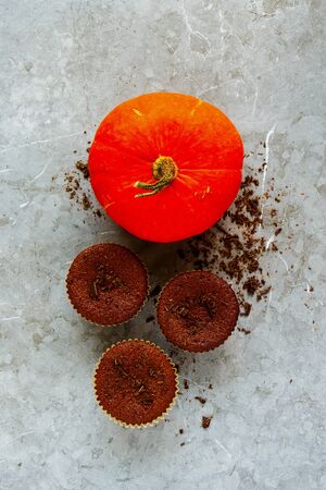 Orange pumpkin and chocolate pumpkin cupcakes on grey concrete backgroundの写真素材
