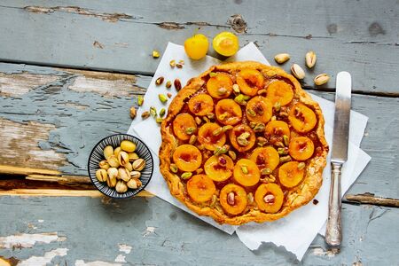 Flat-lay of yellow plum tart on wooden boardの写真素材