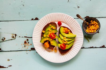 Healthy vegan toasts in plate with avocado and corn flat layの写真素材