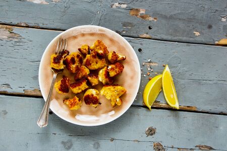 Roast cauliflower in plate on wooden table flat lay. Delicious healthy snack top viewの写真素材