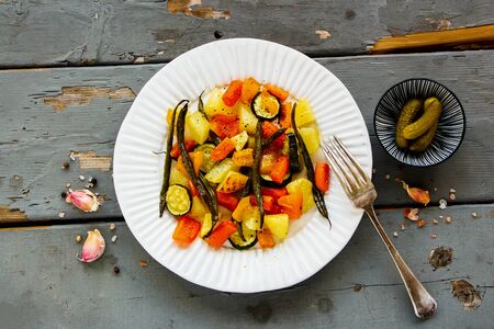 Plate with potatoes, carrots, green beans and zucchini on wooden table flat layの写真素材