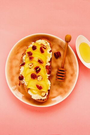 Toast with apple, nuts, honey and ricotta on pink background flat layの写真素材
