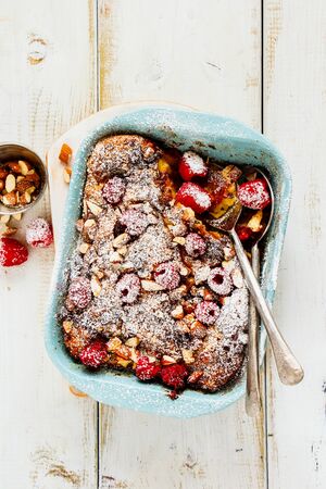 Flat lay of croissant casserole with almonds and raspberries on wooden table from aboveの写真素材