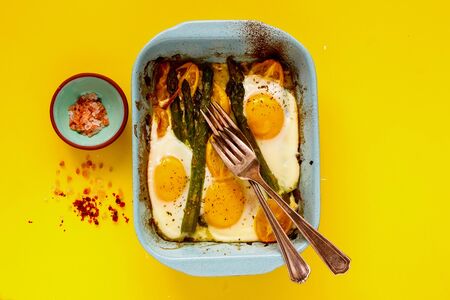 Flat-lay of baked vegetables and eggs on yellow background の写真素材