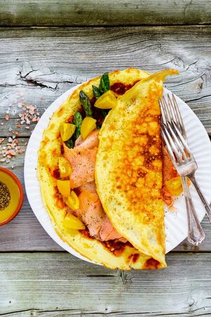 Omelette with smoked salmon and vegetables on wooden table flat layの写真素材