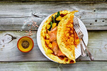 Omelette with smoked salmon and asparagus on wooden table flat layの写真素材
