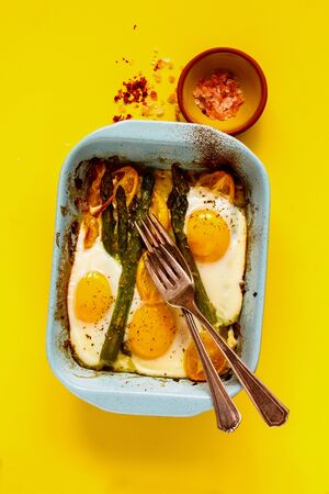 Baked vegetables and eggs on yellow background flat-layの写真素材