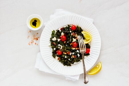 Healthy salad with kale, feta, nuts and tomato on white background flat layの写真素材