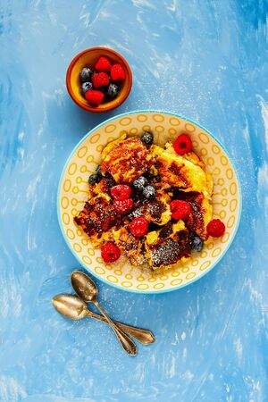 Shredded pancake with fresh berries on blue board from above flat layの写真素材
