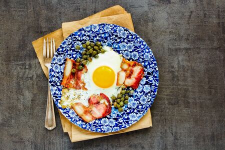 English breakfast with fried egg and bacon on vintage background flat layの写真素材