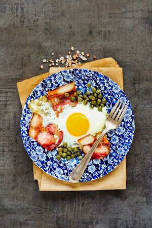Tasty english breakfast with fried egg and bacon on vintage background flat layの写真素材
