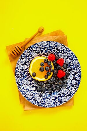 Flat-lay of snack appetizers plate with fruits and berries on yellow backgroundの写真素材