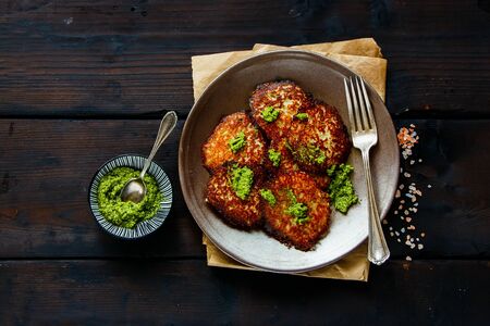 Homemade potato pancakes with pesto sauce on vintage wooden table flat layの写真素材