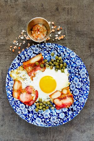 English breakfast in plate with fried egg and bacon flat layの写真素材