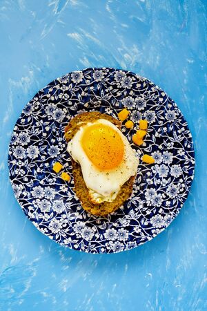 Fried egg sandwich with pesto sauce and sweet corn on blue background flat layの写真素材