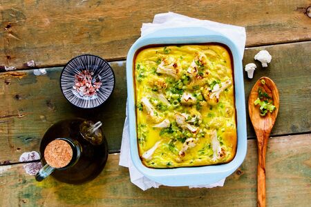 Flat-lay of Cauliflower Gratin in baking dish on wooden board top viewの写真素材