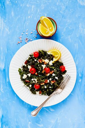 Salad with kale, feta, nuts and tomato on blue background flat layの写真素材